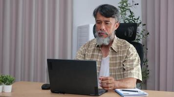 Retired grandfather relaxing with laptop, journaling his daily routine. video