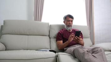 Elderly man in later years journaling, calling a friend, and relaxing at home. video