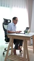 Elderly father using laptop to update news while relaxing in retirement at home. video