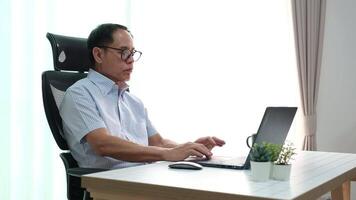 Elderly father using laptop to update news while relaxing in retirement at home. video