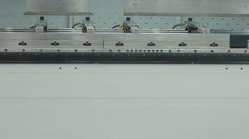 Yellow robotic arms with vacuum suction cups operates in front of a press brake machine showcasing automation in metal bending processes. Advanced automate manufacturing high precision technology video