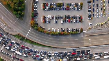 An Aerial View of a Busy Parking Lot and Traffic Flowing Around It. Timelapse video