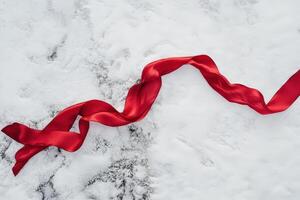 Red ribbon gracefully flows on snowy ground photo