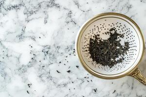 Loose leaf tea in antique strainer on marble photo