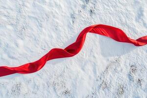 Red ribbon elegantly draped on fresh white snow photo