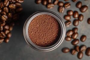 Ground coffee beans in a portafilter beside whole beans photo