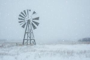 A windmill in the snow on a farm photo