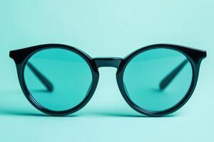 A pair of black sunglasses on a turquoise background photo
