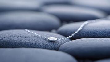 A small silver necklace sitting on top of rocks photo
