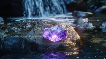 A purple stone is sitting on a rock in front of a waterfall photo