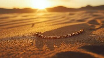 A gold chain laying in the sand at sunset photo