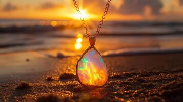 A tear shaped opal pendant on the beach at sunset photo
