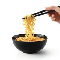 A hand holding chopsticks over a bowl of noodles photo