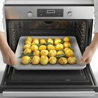 A person is holding a tray of potatoes in an oven photo