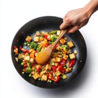 A person holding a wooden spoon over a pan of food photo