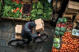 Deliveryman on Bicycle Transports Cardboard Boxes Past Market Produce photo