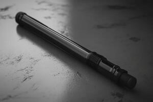 Sleek Black Cylindrical Object Rests On Dark Surface photo