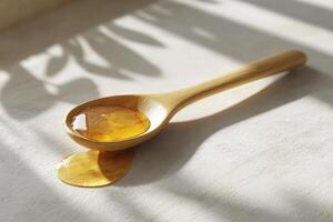 Golden Honey in a Wooden Spoon on White Surface photo
