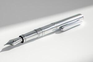 A Shiny Silver Fountain Pen Rests on White photo
