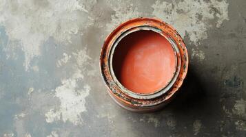 An orange paint can sits on a weathered surface photo