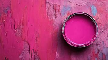 Pink paint in a can on a textured pink surface photo