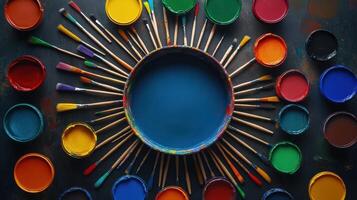 Colorful paint pots and brushes arranged in a circular design photo