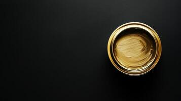 Gold paint in a metallic container on black background photo
