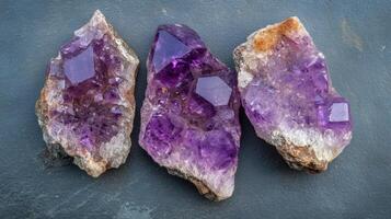 Three Amethyst Geodes Displayed on Dark Surface photo