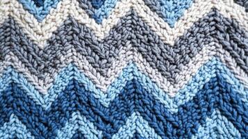 Knitted fabric showing chevron pattern in blues and beige photo