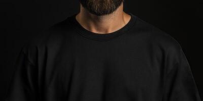 Man with beard in plain black shirt stands against dark background photo