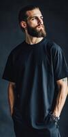 Bearded man poses in black t-shirt on dark backdrop photo