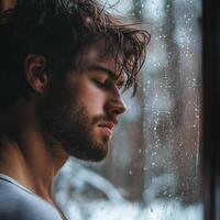 A man looking out a window in the snow photo