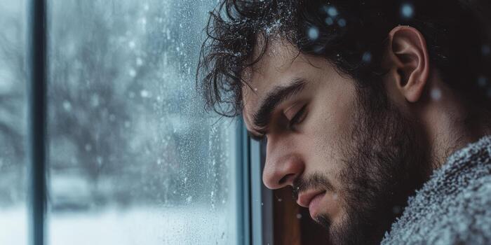 Lonely man gazing out the window during a snowy day photo