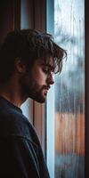 A man looking out a window with raindrops on it photo