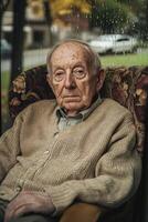 An elderly man sitting in a chair with a rain drop on his face photo