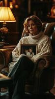 Woman in cozy sweater holding a family photo by a warm lamp