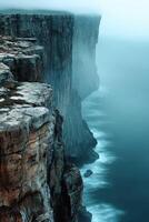 Fog envelops rugged cliffs by the coastline at dawn photo
