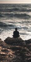 Meditation at the shore during sunset on a rocky coastline photo