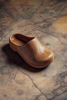 Unique wooden clogs displayed on textured surface in natural light photo