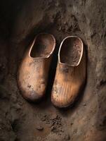 Vintage wooden clogs resting in earthy soil with texture photo