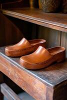 A pair of brown clogs on a wooden shelf photo