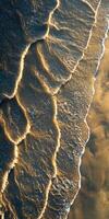 Waves gently lapping on a golden shoreline at sunset photo