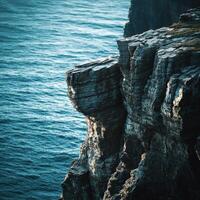 A person standing on a cliff overlooking the ocean photo