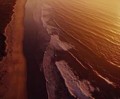 Aerial view of the ocean and beach at sunset photo