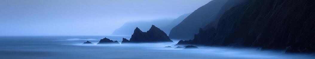 A dark ocean with rocks and fog photo