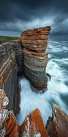 A rocky cliff with waves crashing against it photo