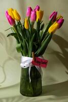 HAPPY EASTER paper greeting card Multicolored fresh tulips in vase in green background with trendy deep shadows. Spring flowers in yellow and violet colors. Postcard wallpaper design Copy space photo