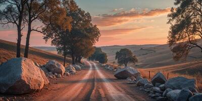 Road with large rocks obstructing the path during sunset in a rural landscape with trees on the side and rolling hills in the background Copy Space. photo