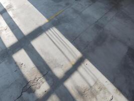 Light and shadow cut the weathered concrete floor space photo