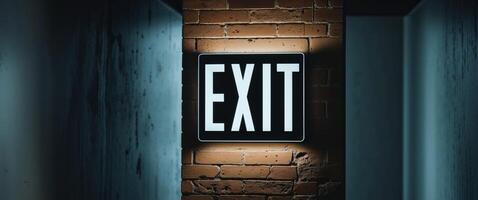 Bright exit sign glowing on a brick wall in a dimly lit corridor photo